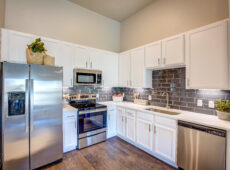 Kitchen with white cabinets, grey backsplash and stainless steel appliances